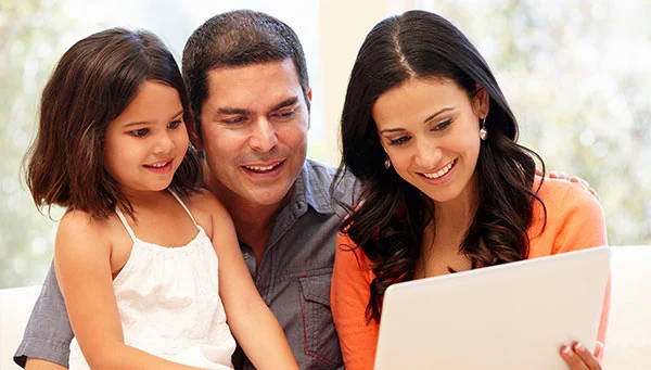 Smiling family looking at a laptop computer.