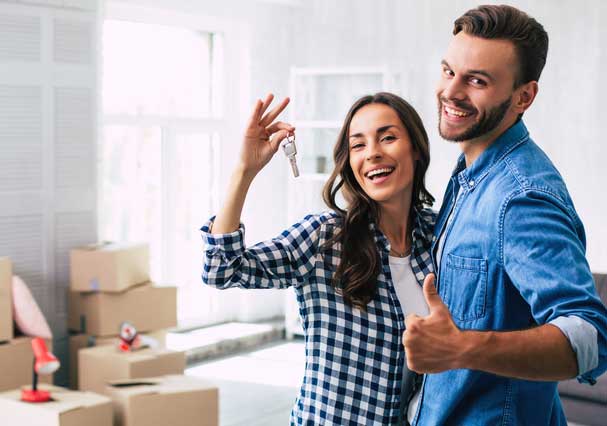 woman and man showing keys to their new home